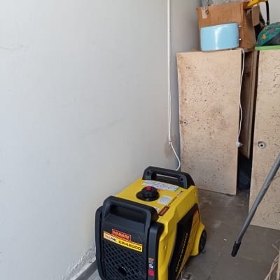 גנרטור צהוב על רצפה ליד קיר עם חוטי חשמל