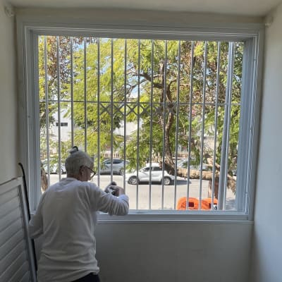 אדם עובד על מסגרת חלון עם סורגים