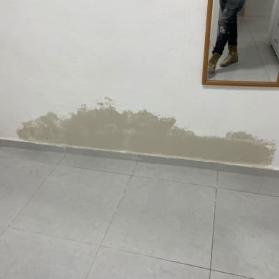 קיר עם תיקון טיח, רצפה מרוצפת, מראה עם השתקפות רגליים