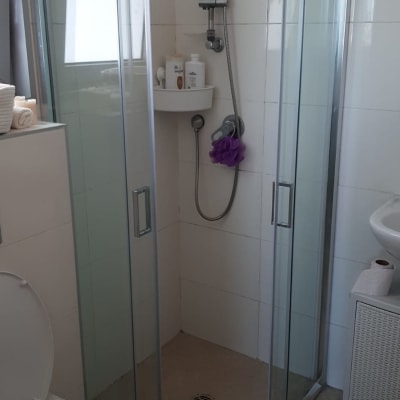 מקלחון זכוכית עם ראש מקלחת ומדף מוצרים