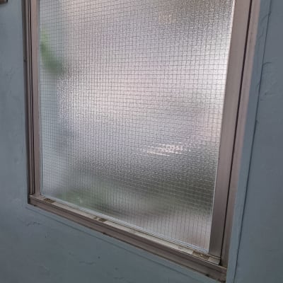 חלון זכוכית עם מסגרת מתכת על קיר כחול