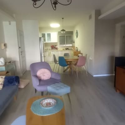 חדר מגורים עם רהיטים צבעוניים ותאורה תלויה