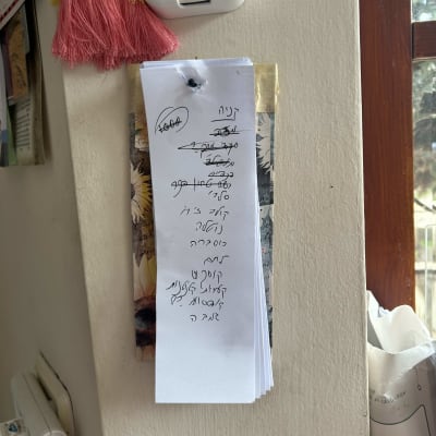 פתק עם רשימת קניות תלוי על הקיר ליד מתג חשמל.