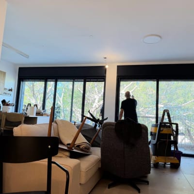 אדם מנקה חלון בסלון עם סולם ושואב אבק