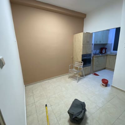 קיר צבוע בצבע חום עם כלי צביעה על הרצפה