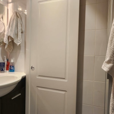 דלת הזזה לבנה עם ידית עגולה בחדר אמבטיה