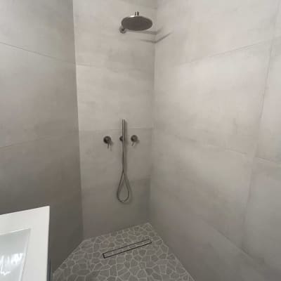 מקלחת עם אריחים אפורים וראש מקלחת עגול