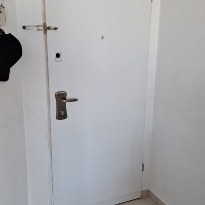 דלת לבנה עם ידית מתכת וחור מנעול