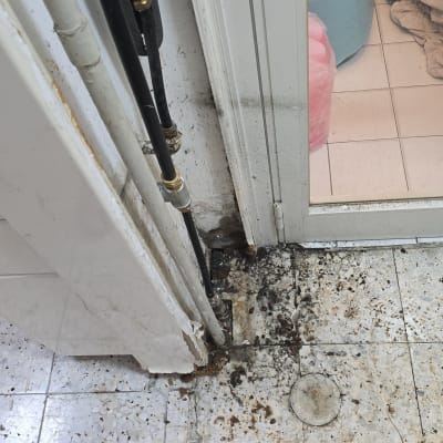 צינורות מים ליד דלת עם סימני רטיבות על הרצפה