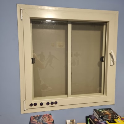 חלון עם תריסים לבנים סגורים על קיר כחול