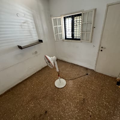 מאוורר עומד בחדר ריק עם חלון ודלת