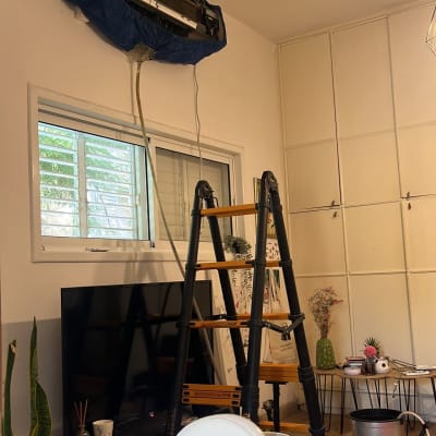 מזגן מפורק עם כיסוי כחול, סולם שחור לידו