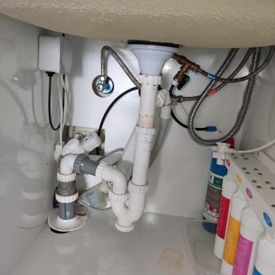 צנרת מתחת לכיור עם מחברים וברזים