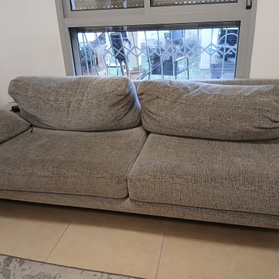 ספה אפורה ליד חלון עם סורגי מתכת