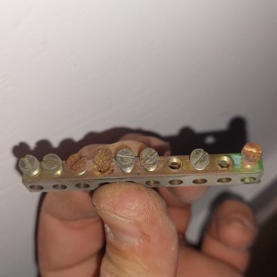 פס מתכת עם ברגים חלודים מוחזק ביד