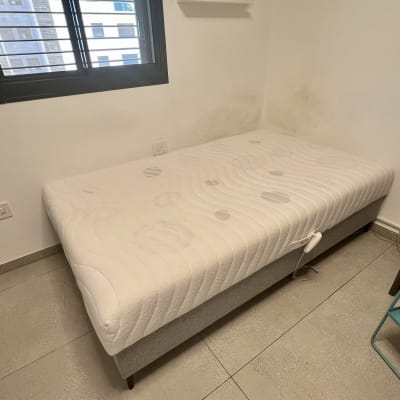 מיטה בחדר עם חלון וארון קטן