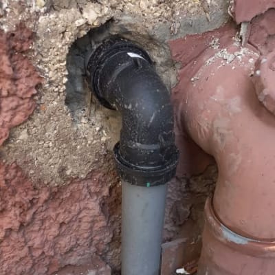 צינור פלסטיק שחור מחובר לקיר עם חיבורי אינסטלציה