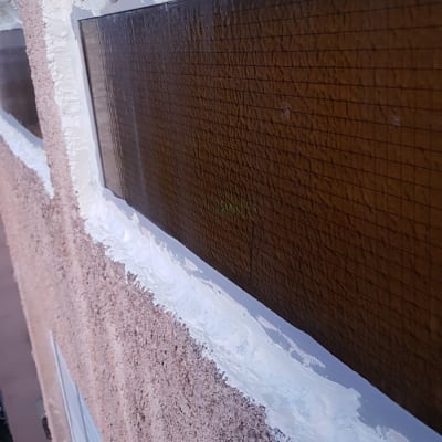 חלון עם איטום לבן על מסגרת חומה