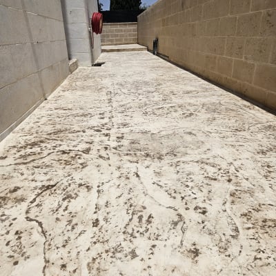 משטח בטון עם קיר אבן וצינור מים אדום