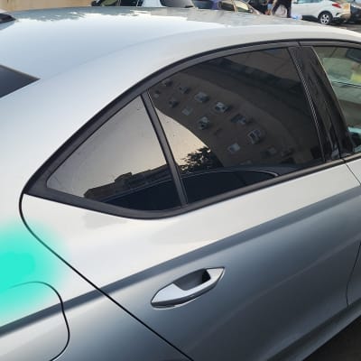 חלון צד של רכב כסוף עם השתקפות בניין