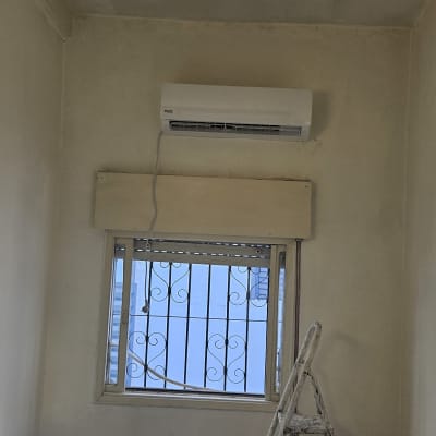 מזגן מותקן על קיר מעל חלון עם סולם