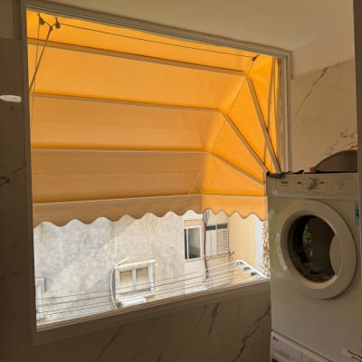 סוכך כתום מותקן מעל חלון עם חבלים