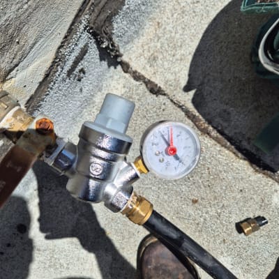 מד לחץ מים מחובר לצינור על רקע בטון