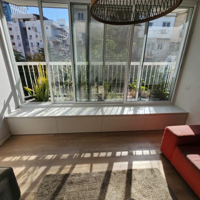 חלון גדול עם אדן מעץ וצמחייה בחוץ