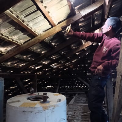 אדם בודק גג רעפים מעץ עם פנס