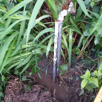 ברז מים בגינה עם צינור חשוף באדמה