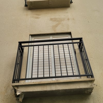 מרפסת עם מסגרת מתכתית וחלון עם תריסים