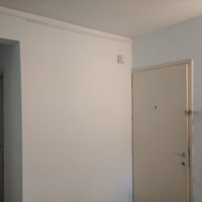 קיר צבוע בלבן עם דלת ומקל צביעה