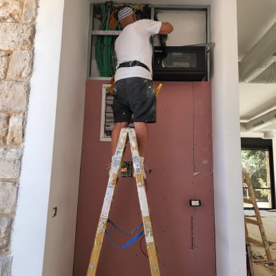 אדם עובד על קיר גבס עם כבלים חשמליים