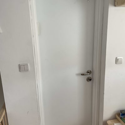 דלת לבנה עם ידית מתכת כסופה ומתג חשמל