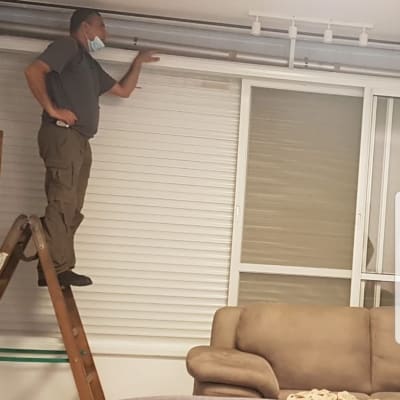 אדם על סולם מתקין תריסים בחלון