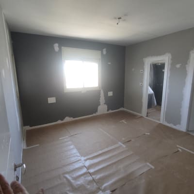 חדר עם קירות צבועים חלקית ונייר על הרצפה