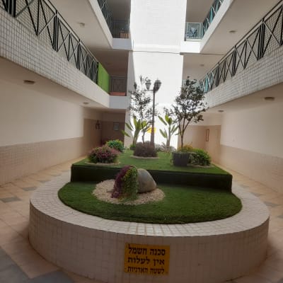 גינה פנימית עם עצים, שיחים ודשא מלאכותי