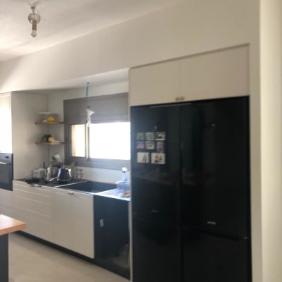 מטבח עם מקרר שחור, כיור וכלי מטבח על השיש