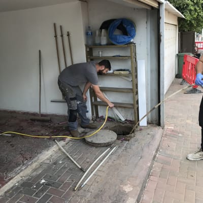 אדם עובד עם צינור ליד בור פתוח