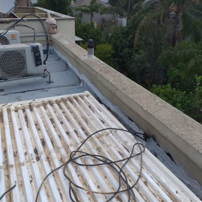 גג עם חומר איטום ליד מזגן וכבלים