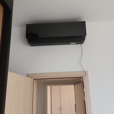 מזגן שחור מותקן על קיר עם כבל חשמל לבן