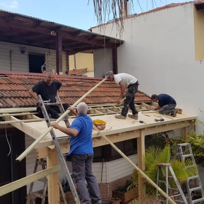 עובדים מתקנים גג רעפים עם קורות עץ וסולם