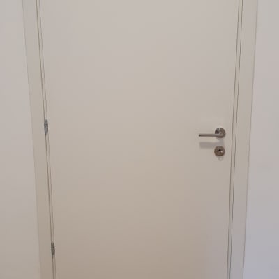 דלת לבנה עם ידית מתכת ורצפת עץ