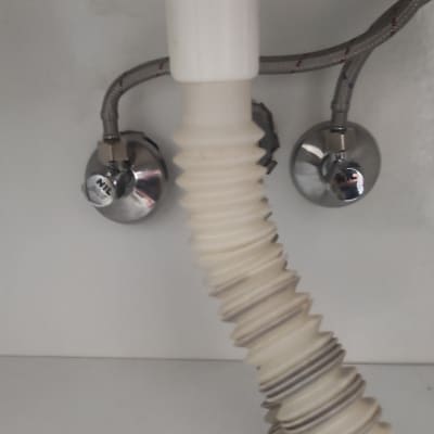 צינור פלסטיק מתחת לכיור עם ברזים מתכתיים