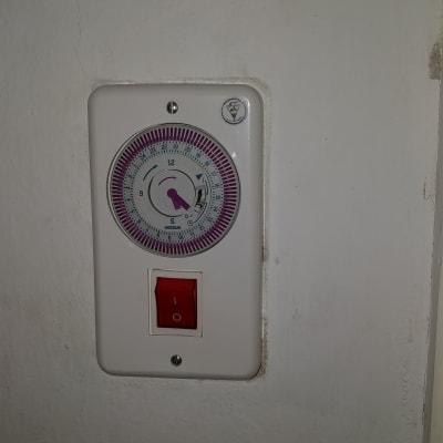 טיימר חשמלי עם מתג אדום על קיר לבן