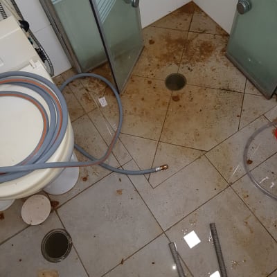 צינורות וכלים על רצפת חדר אמבטיה מלוכלכת