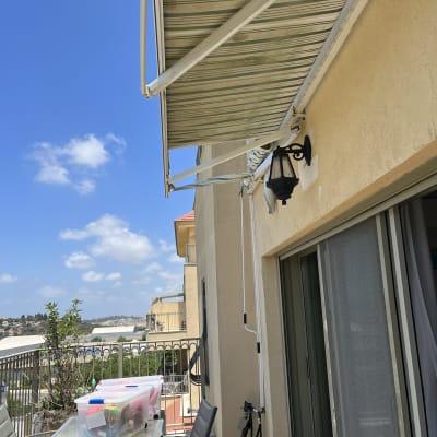 סוכך בד לבן וירוק מותקן על קיר חיצוני