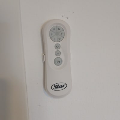 שלט רחוק לבן עם כפתורים על קיר לבן