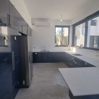 מטבח מודרני עם ארונות כהים ומשטחי עבודה לבנים