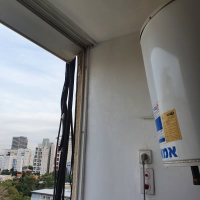 קיר צבוע בלבן עם דוד חשמלי ושקע חשמל